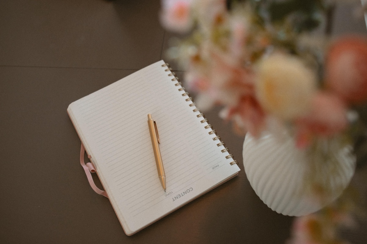 A therapy notebook and gold pen beside a soft floral arrangement